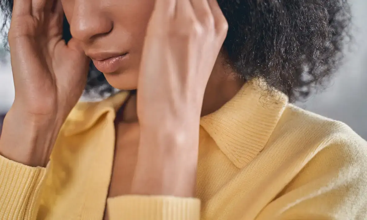 Woman pressing her temples, appearing to have a headache