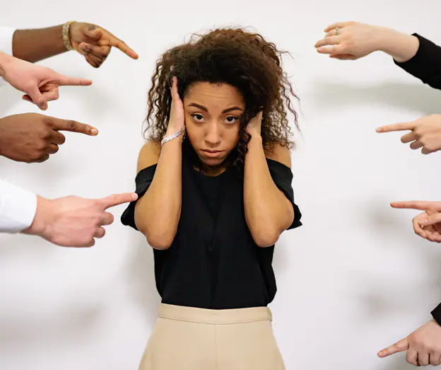 Stressed professional covering her ears as multiple hands point fingers
