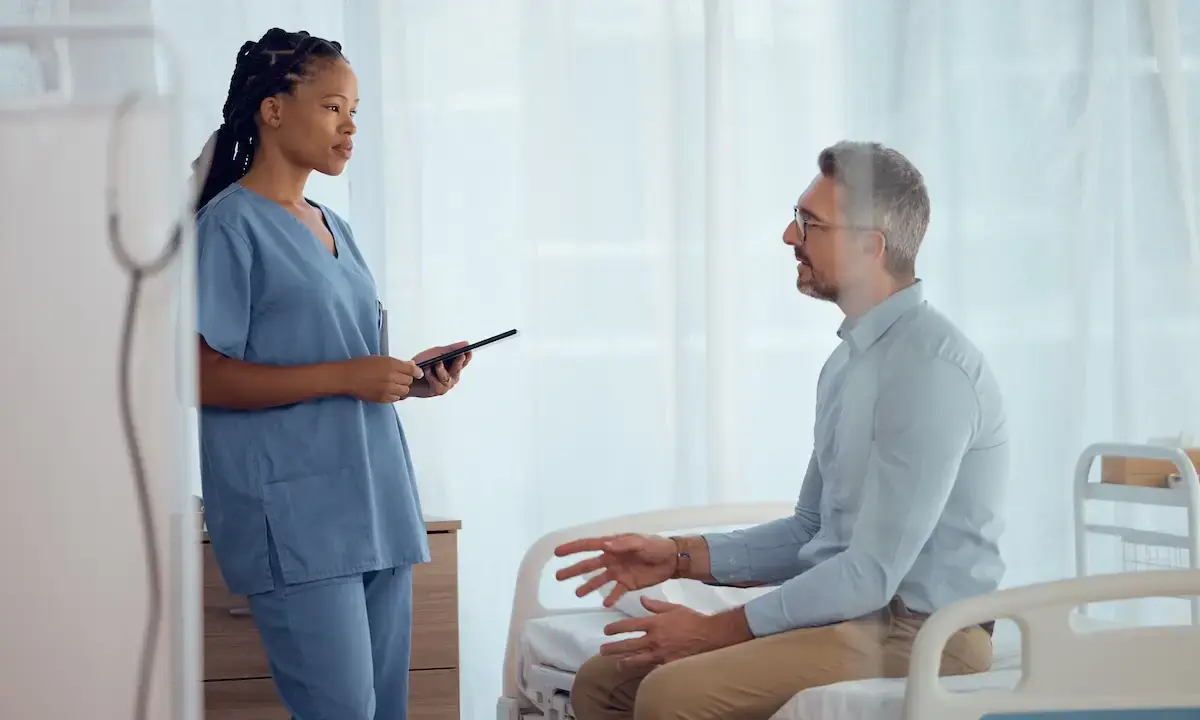 Nurse discussing hospital care with seated male patient