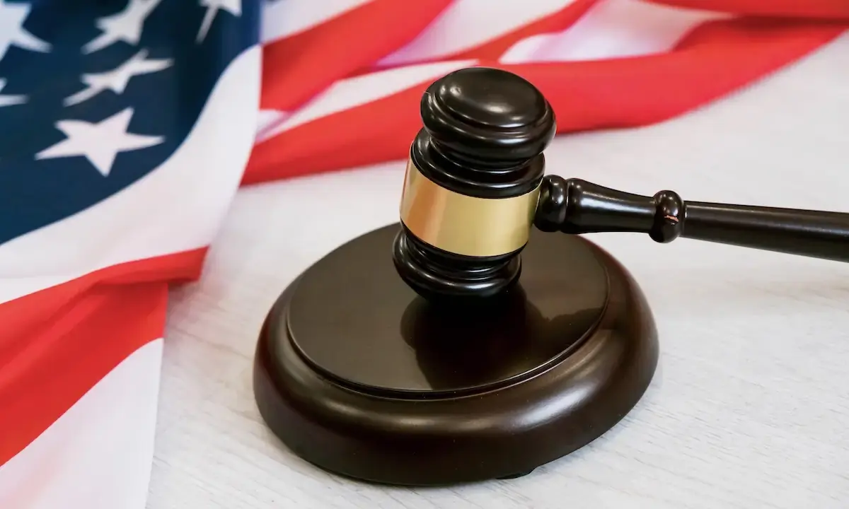 Judge's gavel on sounding block beside draped U.S. flag
