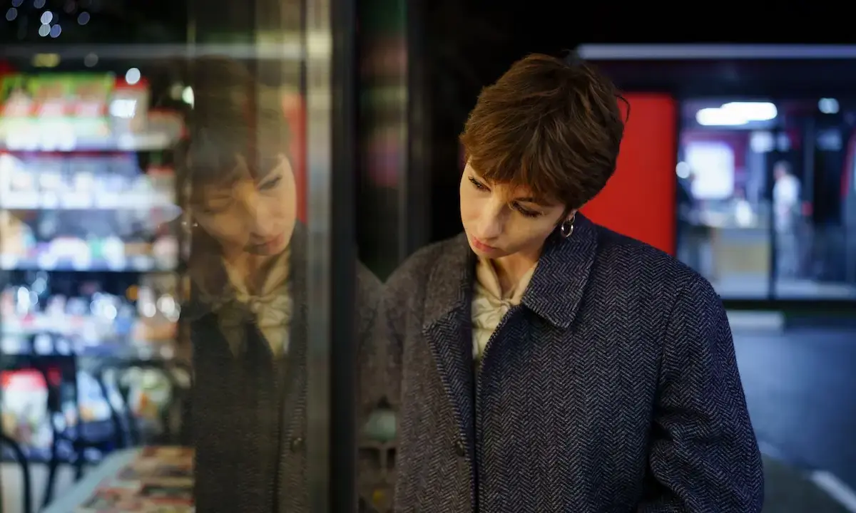 Woman gazing at her reflection in a shop window at night