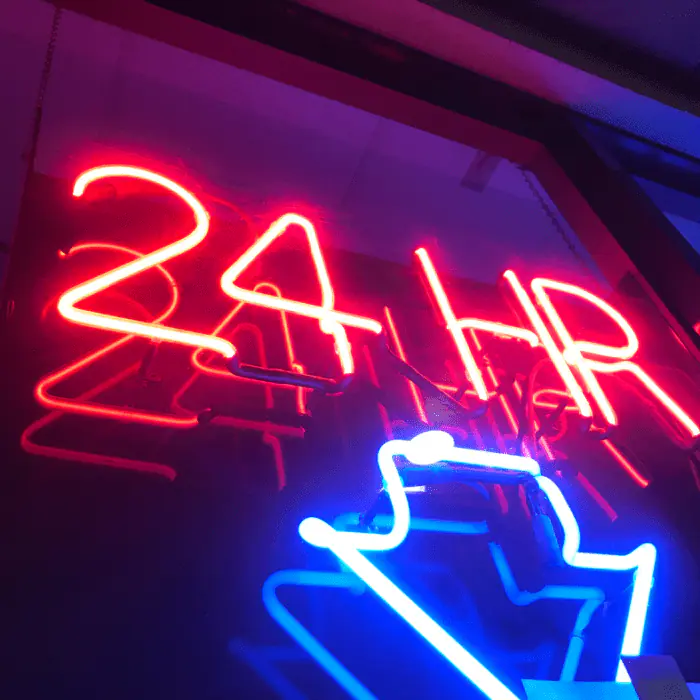 Red neon '24HR' sign and blue neon symbol suggesting 24-hour detox support