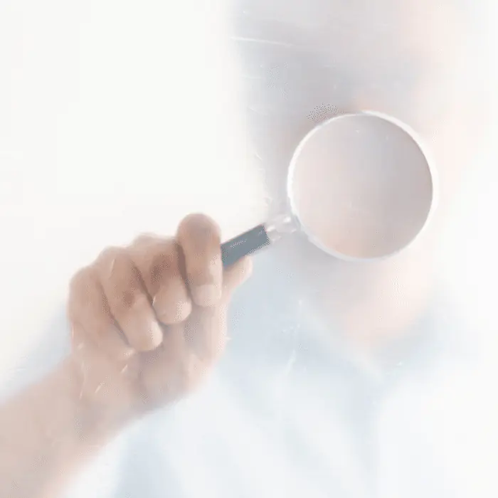 Hand holding magnifying glass symbolizing close scrutiny of cold-turkey detox risks